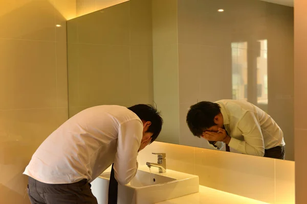 Un uomo asiatico che lava il viso in bagno, bagno di lusso, persona — Foto Stock