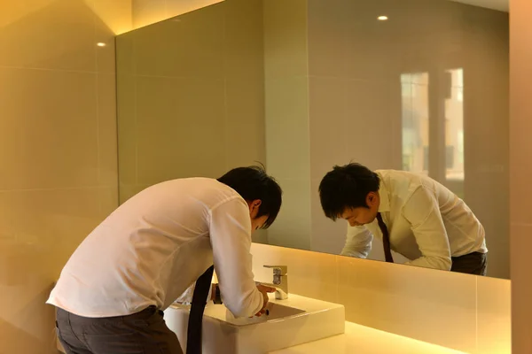 Um homem asiático lavando o rosto no banheiro, banheiro de luxo, pessoa — Fotografia de Stock