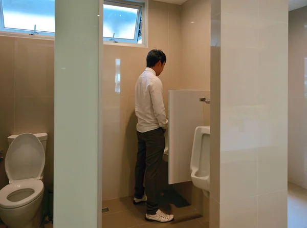 Un homme d'affaires asiatique urine dans la salle de bain, personne — Photo