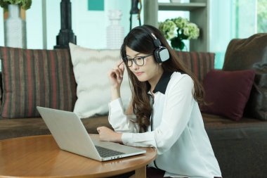 Bir dizüstü bilgisayar kullanarak ve müzik, iş Asyalı kız kişi