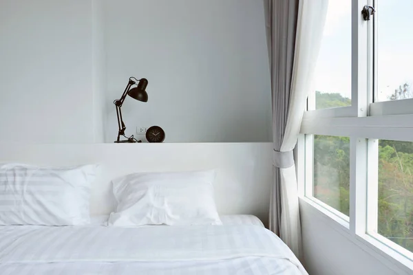Lámpara moderna en la mesita de noche de madera en el dormitorio moderno blanco, interi — Foto de Stock