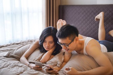 Kendi telefonunu kullanarak ve masa telefonlarına, gülümseyen Asya çift