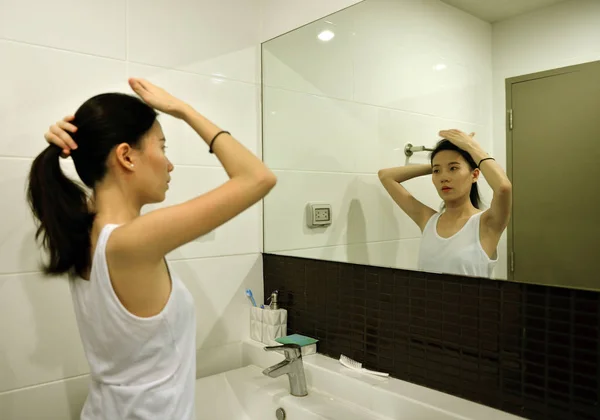 Asyalı kadın banyoda ayna önünde saç fırçalama — Stok fotoğraf