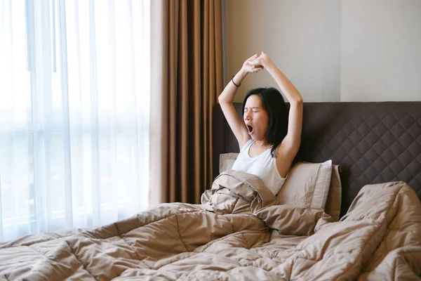 Asiatico donna sbadigliare e risveglio su letto in lusso camera da letto in th — Foto Stock