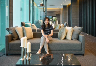 Asyalı kadın Odalı Villa kanepe üzerinde gülümseyen