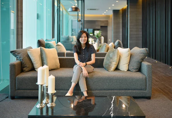 Asiatico donna sorridente su divano in lusso condominio — Foto Stock