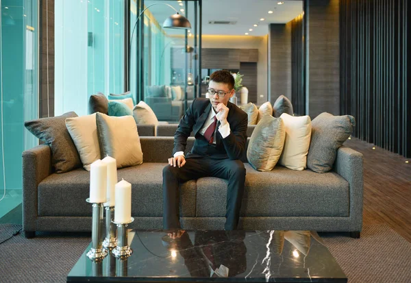 Business homme asiatique est stressé et nerveux, penser sur le canapé — Photo