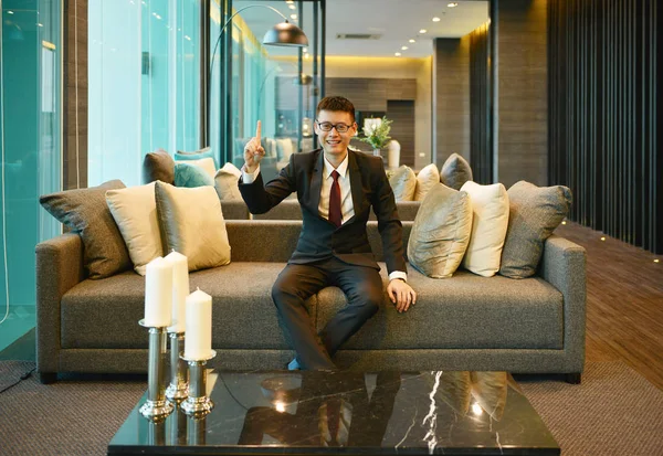 Homem de negócios asiático apontando no sofá no condomínio de luxo — Fotografia de Stock