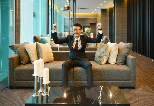 Homem de negócios asiático sorrindo no sofá no condomínio de luxo — Fotografia de Stock