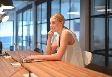 Bir ofiste bir dizüstü bilgisayar kullanan iş sarışın kız