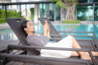 Güzel gülümseyen kadın chaise Yüzme Havuzu yanında yatan Tay