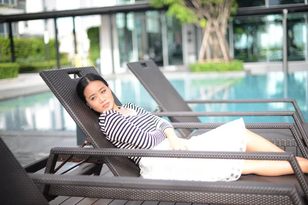 Belle femme thaïlandaise souriante allongée sur une chaise longue près de la piscine — Photo