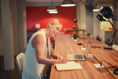 Bir ofiste bir dizüstü bilgisayar kullanan iş sarışın kız