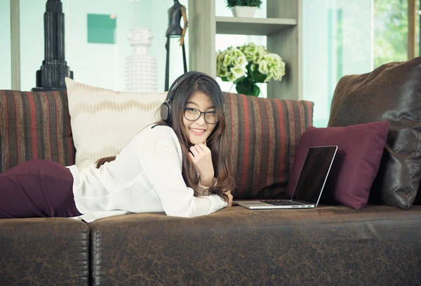 商业亚洲女孩靠在沙发上使用笔记本电脑 — 图库照片