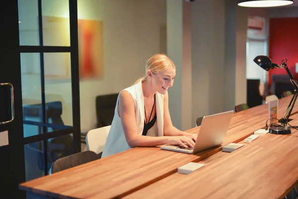 Business blonde girl using a laptop in an office — Stock Photo, Image