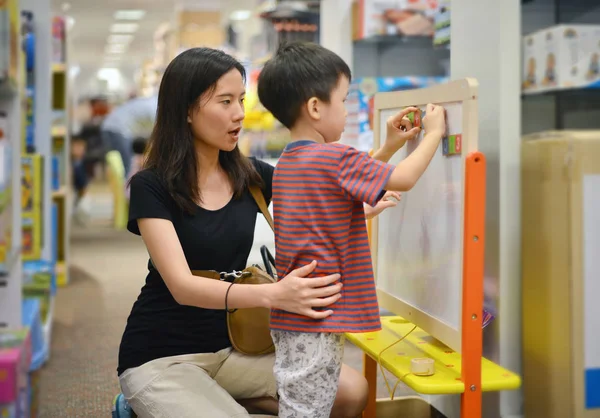 Ung asiatisk mamma och hennes kid shopping leksak i köpcentrum — Stockfoto