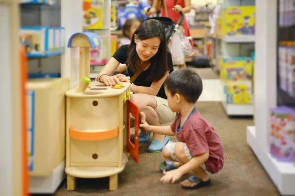 Ung asiatisk mamma och hennes kid shopping leksak i köpcentrum — Stockfoto