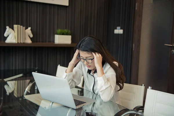 Μια γυναίκα της Ασίας επαγγελματίες τόνισε χρησιμοποιώντας ένα φορητό υπολογιστή στο γραφείο — Φωτογραφία Αρχείου