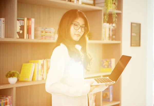 Üzleti ázsiai lány hajol, és használ egy laptop könyvtár — Stock Fotó