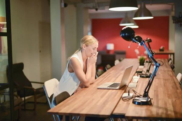 Счастливая деловая блондинка с ноутбуком в офисе — стоковое фото