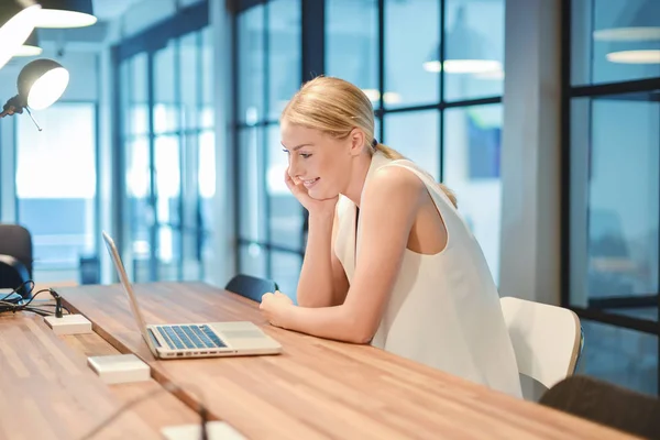 Happy business blonde girl using a laptop in an office — Stock Photo, Image