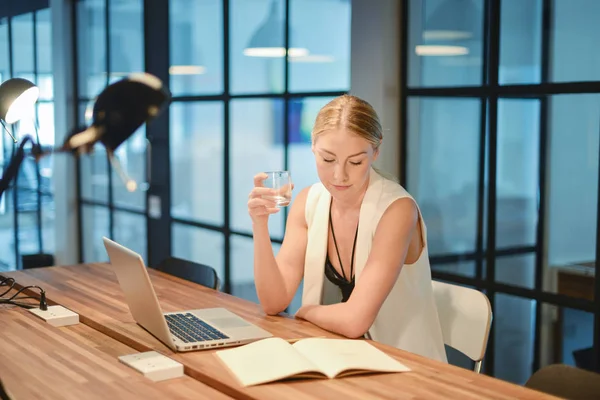 Business blonde girl drinking water in front of a laptop — Stock Photo, Image