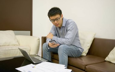 Geceleri oturma odasında bir dizüstü bilgisayar kullanarak Asya iş adamı