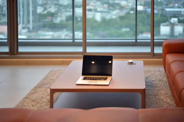 空白の画面を持つモダンなリビング ルームのテーブルの上のノート パソコン — ストック写真