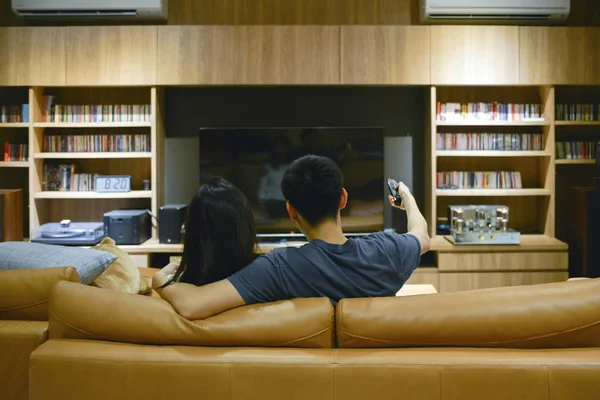 Happy couple watching a movie in living room at night