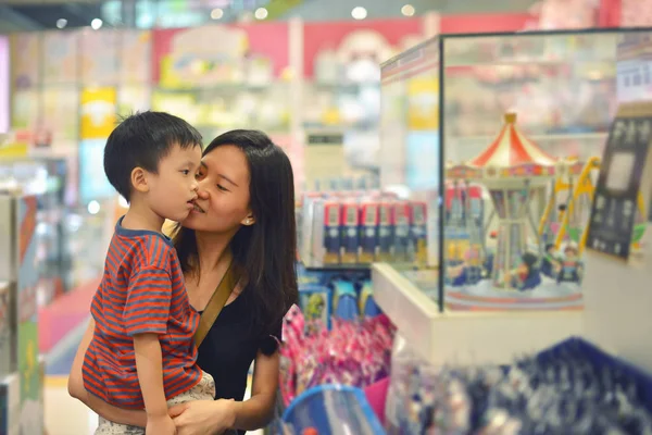 Ung asiatisk mamma och hennes kid shopping leksak i köpcentrum — Stockfoto