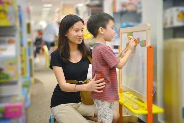 Ung asiatisk mamma och hennes kid shopping leksak i köpcentrum — Stockfoto