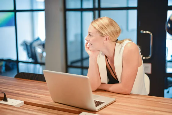 Business blonde girl using a laptop in an office — Stock Photo, Image