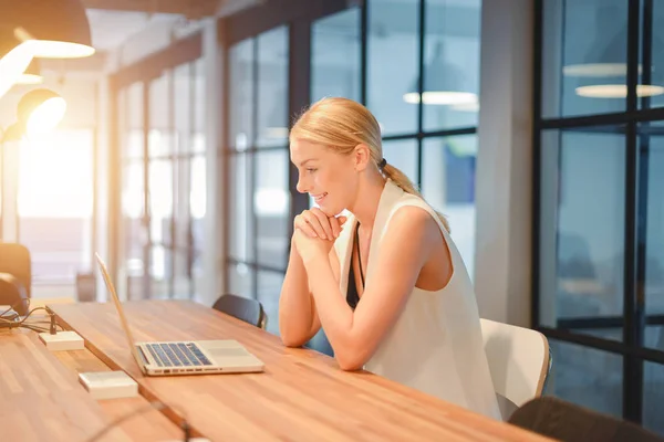 Happy business blonde girl using a laptop in an office — Stock Photo, Image