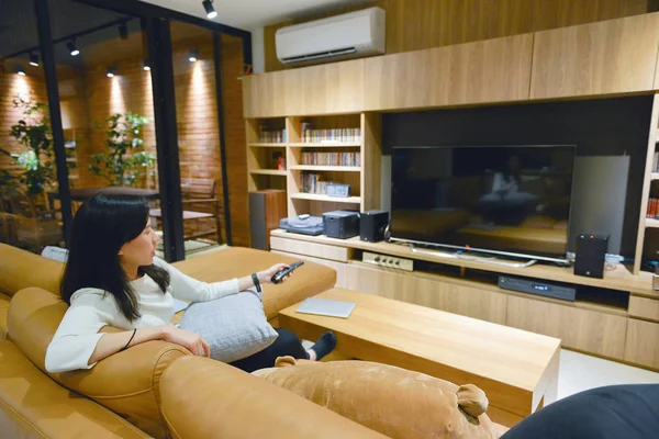 Азіатський жінка за допомогою пульта дистанційного керування до телевізора з пустим екра — стокове фото