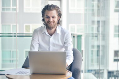 Oturma odasında bir dizüstü bilgisayar kullanarak mutlu Batı işadamı