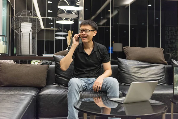Boldog ázsiai üzletember, beszélt a telefont, és a livin laptop — Stock Fotó