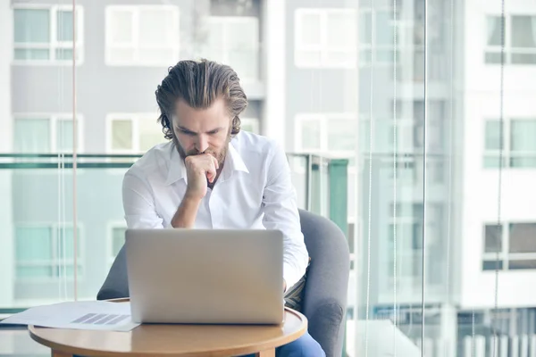 Betonade västra affärsman använder en bärbar dator i vardagsrummet — Stockfoto