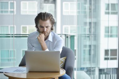 Oturma odasında bir dizüstü bilgisayar kullanarak Batı işadamı vurguladı