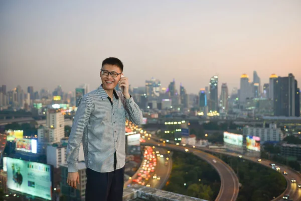 Asian businessman using phone with city  background, technology
