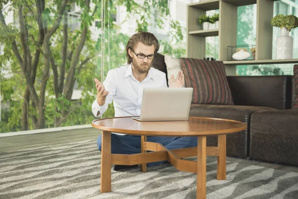 Empresário ocidental estressado usando um laptop na sala de estar — Fotografia de Stock