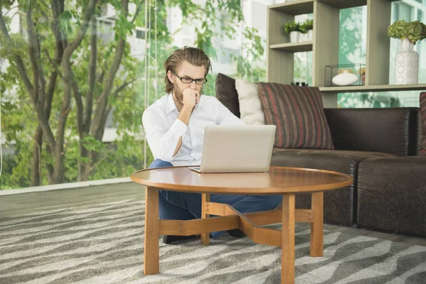 Betonade västra affärsman använder en bärbar dator i vardagsrummet — Stockfoto