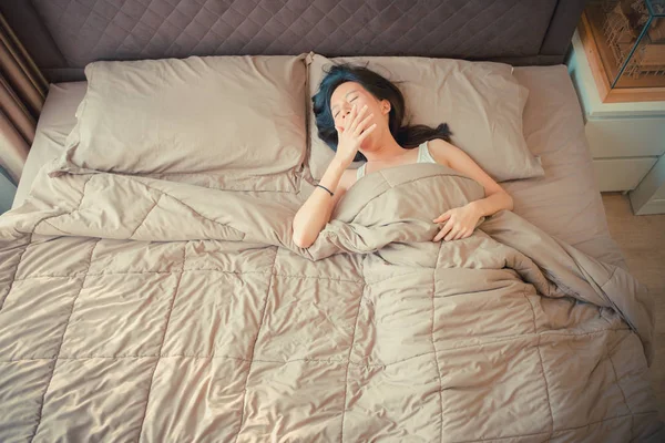 Álmos ázsiai nő Ásító ágyon, felülnézet — Stock Fotó