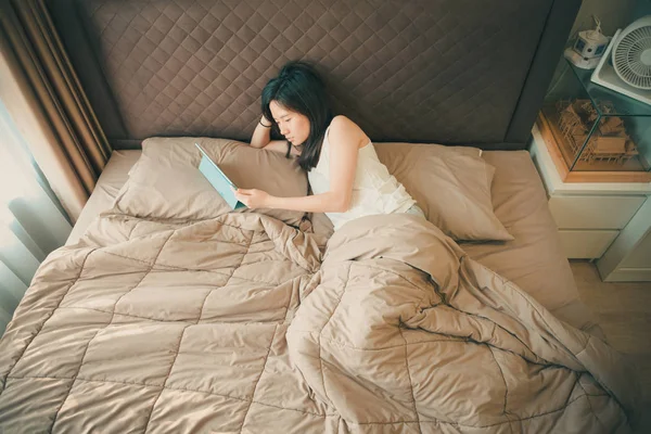 Donna asiatica che soffre di depressione sul letto con un tablet — Foto Stock