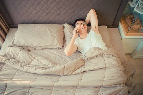 Felice uomo asiatico parlando al telefono sul letto — Foto Stock