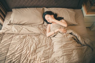Uykulu Asyalı kadın yatakta, üstten görünüm yatarken