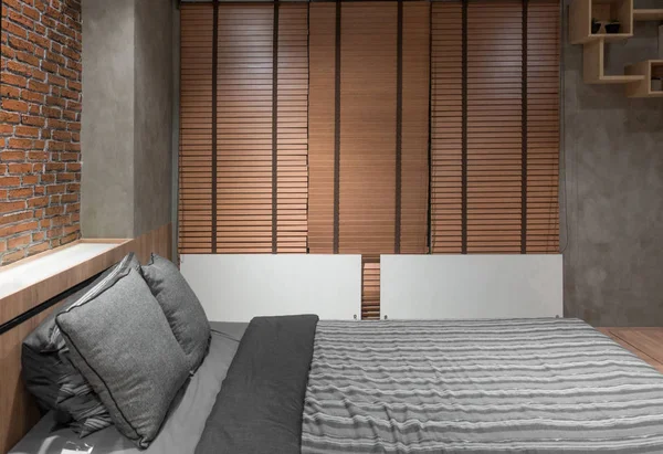 Dormitorio loft con cama cerca de la pared de ladrillo y cortina de madera — Foto de Stock