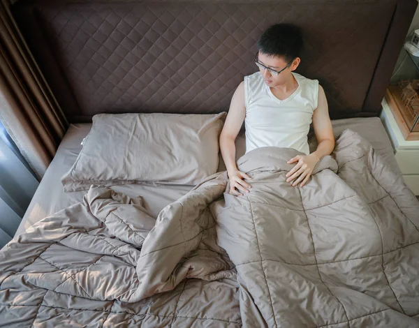 Przygnębiony azjatycki człowiek cierpi na łóżko w sypialni — Zdjęcie stockowe