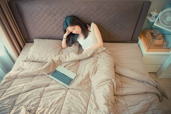 Donna asiatica che soffre di depressione sul letto con un computer portatile — Foto Stock