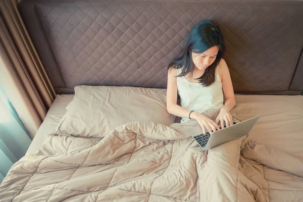 Estressado mulher asiática usando um laptop na cama no quarto — Fotografia de Stock