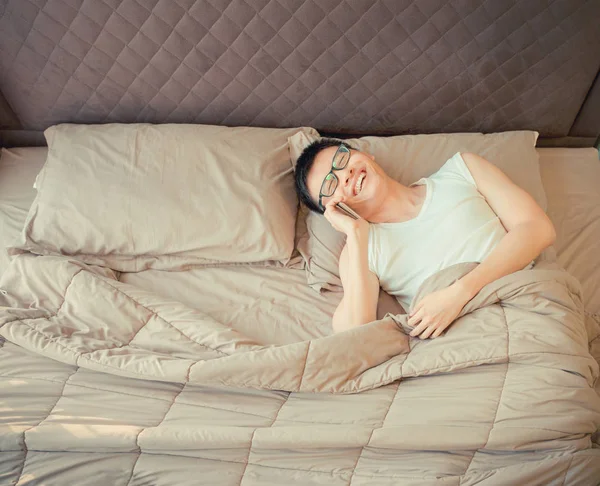 Gelukkig Aziatische man praten over de telefoon op bed — Stockfoto